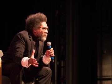 A person speaking into a microphone on a stage.