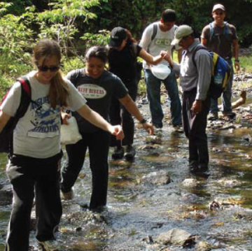 A group of people crossing a shallow stream.