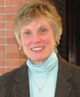 A person smiling in front of a brick wall.