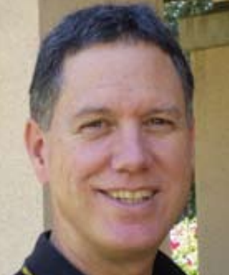 A person smiling outdoors in a headshot photograph.