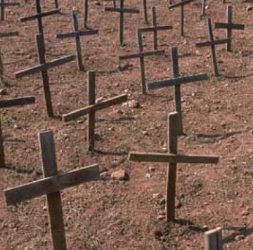 Crosses planted in the ground in a dirt field.
