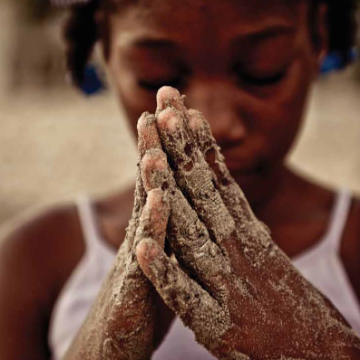 Person with sandy hands clasped together as if in prayer.