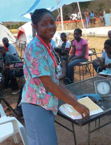 A person smiles while working at a community event in Haiti.