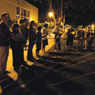 A group of people standing in a line at night, holding hands.