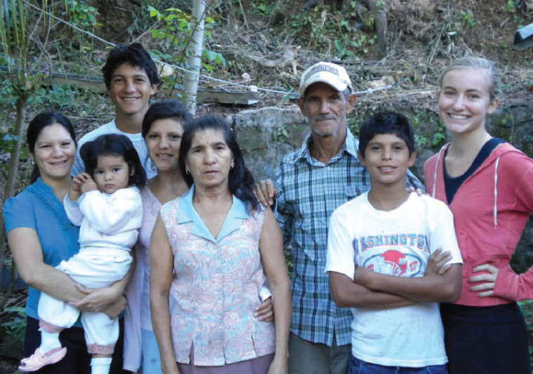 Group of people posing outdoors, with trees in the background.