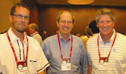 Three people wearing lanyards at an indoor event.