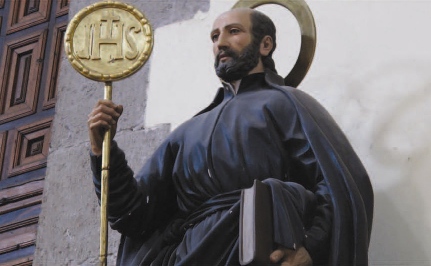 A statue holding a book and a golden staff.