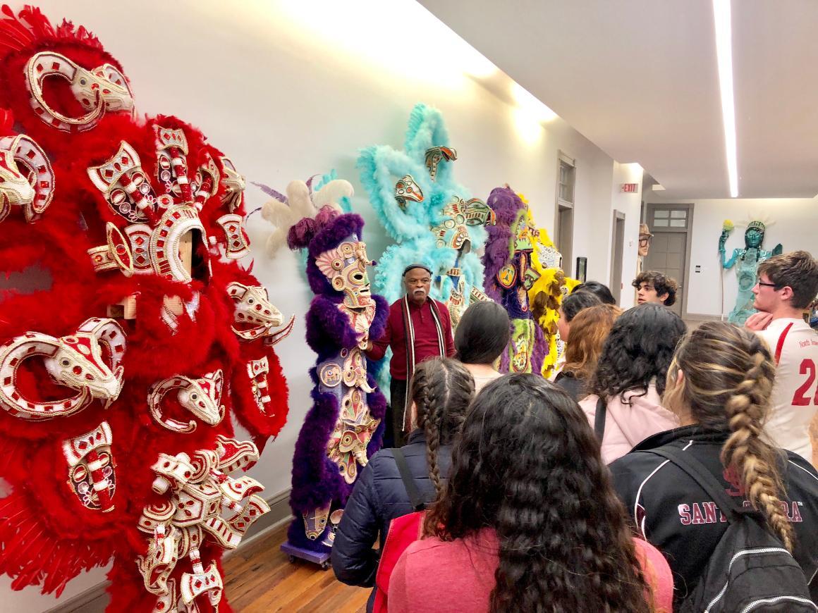 A group of people looking at colorful feathered costumes on display.