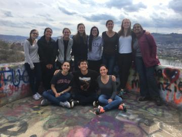 Alt text: Group of people posing outdoors with a scenic, mountainous background.