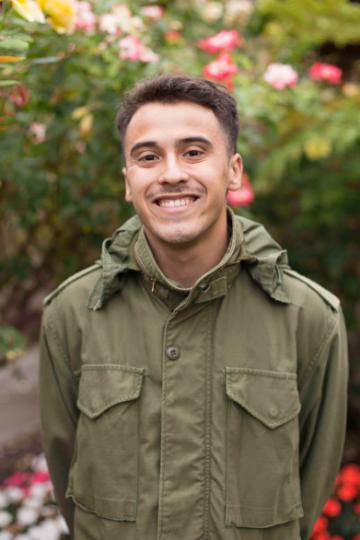 A person in a green jacket standing in a garden.