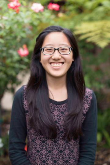 A person smiling in an outdoor garden setting.