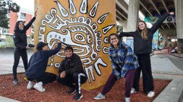 Five people posing in front of the San Diego Immersion Mural.