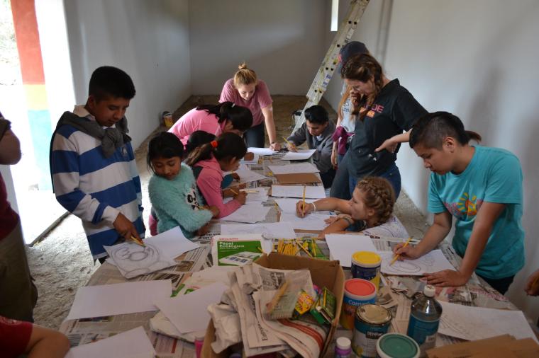 A group of people working together around a table covered with food and papers.
