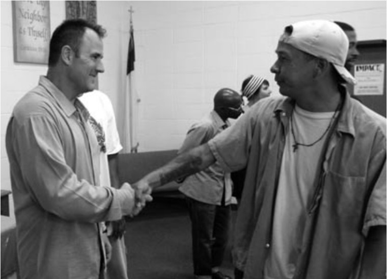 Two men shaking hands in a San Quentin prison setting.