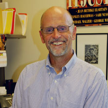 A man with glasses smiling in an office setting.