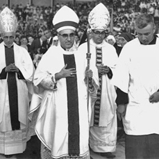 Three clergy members and one person in white robes during a procession.