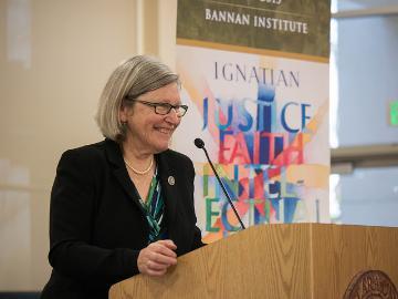 A person speaking at a podium in a gallery.