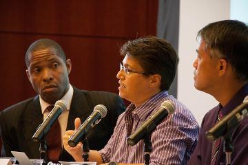 Three individuals seated while discussing, each holding a microphone.