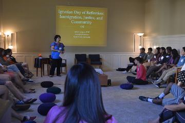 A speaker presenting to an audience in a seated workshop.