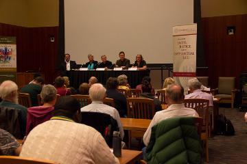 Panel discussion with four speakers in front of an audience in a lecture hall.