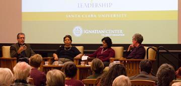 People sitting on a panel in front of an audience.