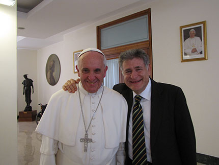 Two people standing together indoors, one in religious attire, smiling at the camera.