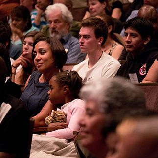 A diverse group of people sitting and watching an event.