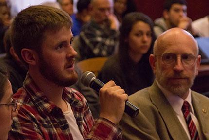 Man speaking into microphone in audience during an event.
