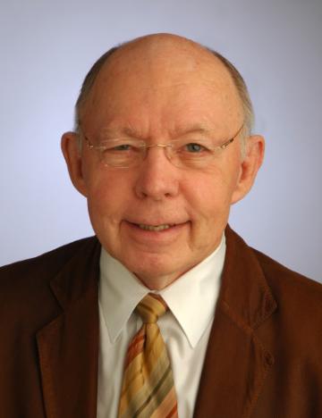 A person wearing glasses, a suit, and a patterned tie. image link to story