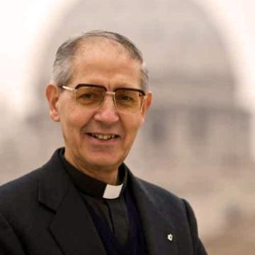 A man in clerical attire with St. Peter's Basilica in background.