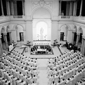 A large gathering in an ornate hall, viewed from above.