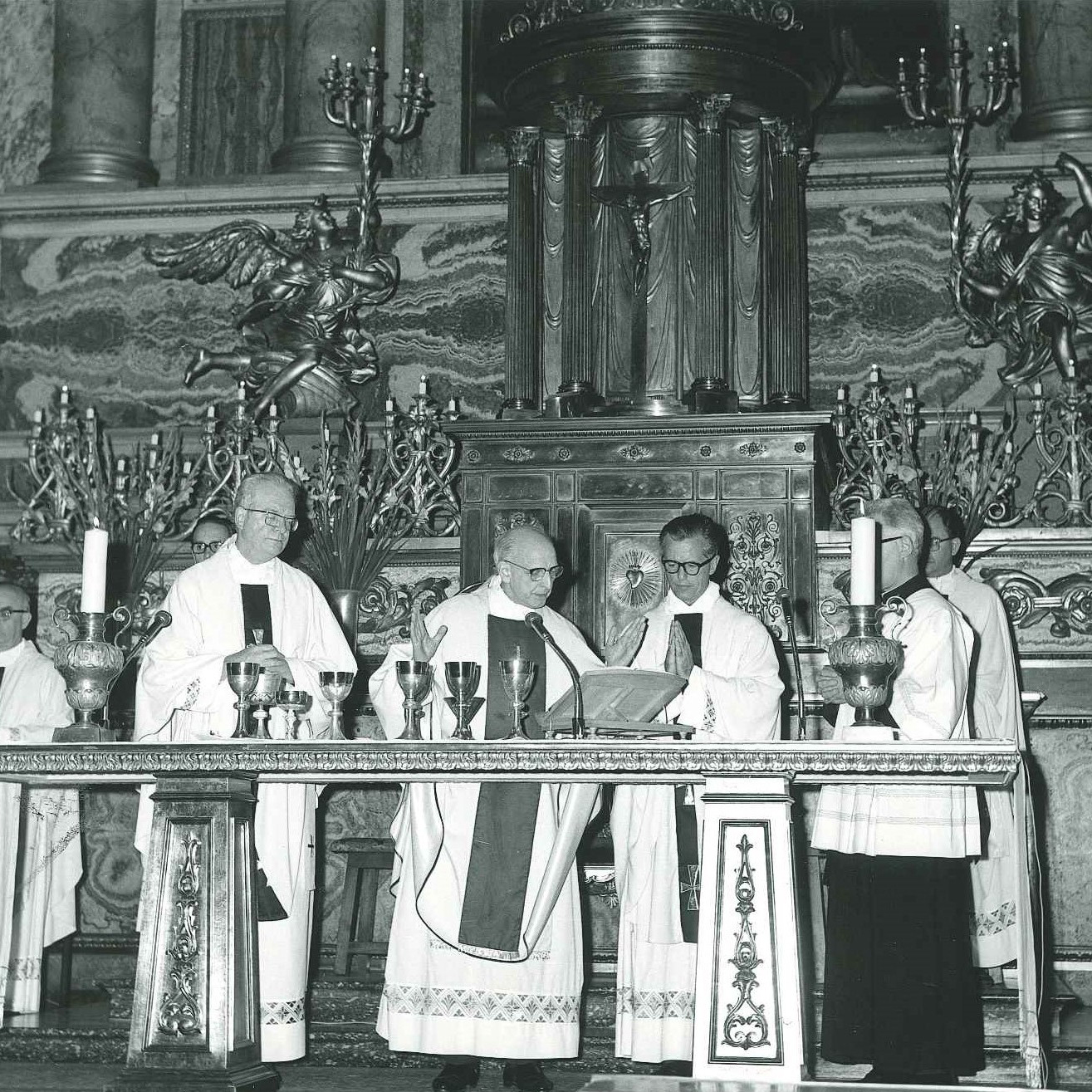 A religious ceremony with four priests at the altar.