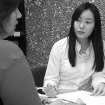 Two individuals discussing documents in a professional setting. image link to story
