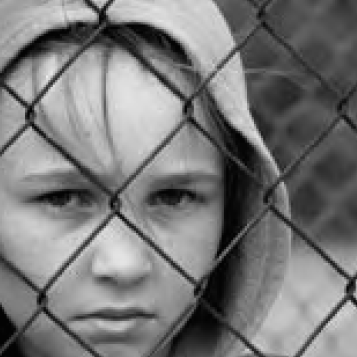 Black and white photo of a person behind a chain-link fence.