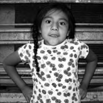 Young girl standing with hands on hips, wearing a floral shirt.