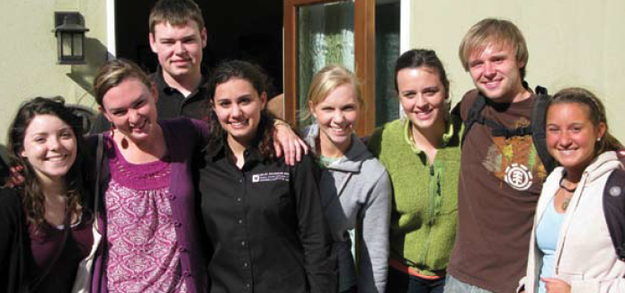 Group of people posing in front of a doorway.