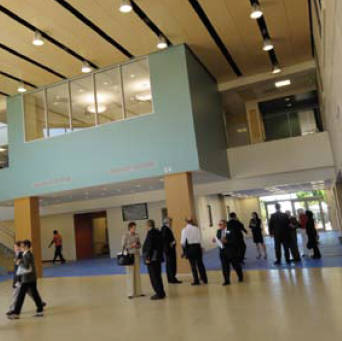 People gathered in a modern campus building lobby with blue carpets. image link to story