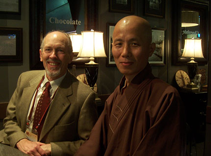 Two people sitting at a restaurant table, smiling at the camera.