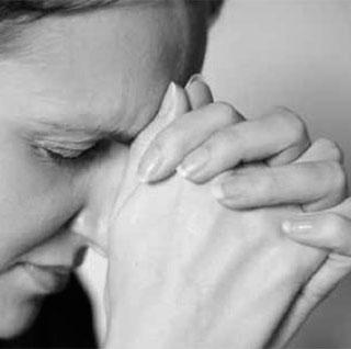 A person with clasped hands in prayer.