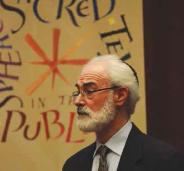 A person speaking in front of a colorful sign.