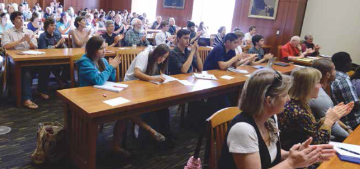 A classroom filled with students seated at desks, engaged in discussion.