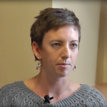 Person wearing a grey shirt with earrings and a microphone.