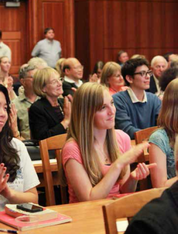 People in an auditorium attentively listening and clapping.