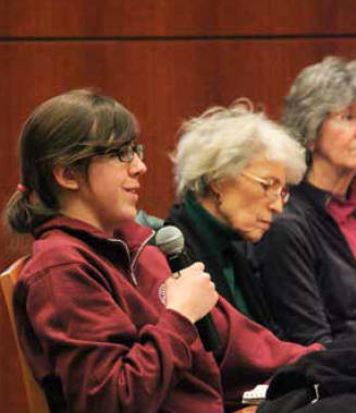 Three people sitting and one person holding a microphone in a panel discussion.