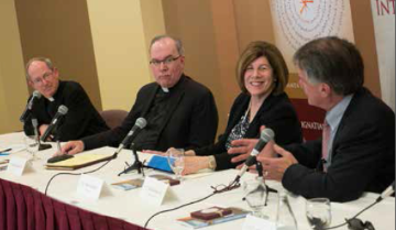Four people engaged in a panel discussion at a conference.