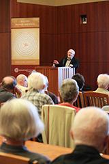 A person speaking at a podium to an audience.