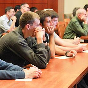 A group of people attentively listening in a classroom setting.