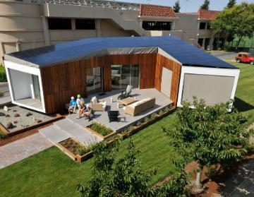 Modern wooden house with solar panels and a large patio.
