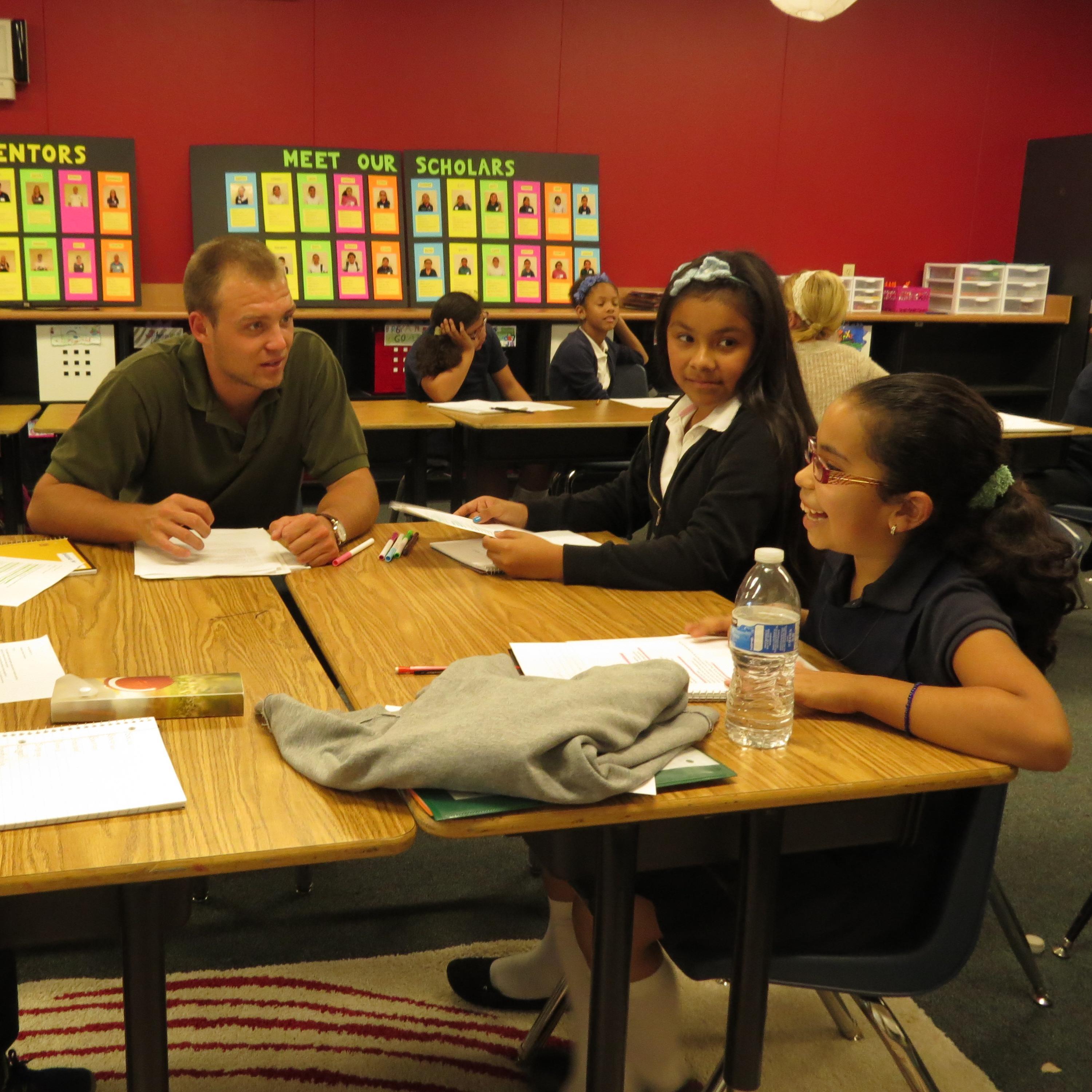 Four people having a discussion around a table in a classroom.