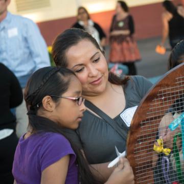A woman and girl closely observing a large decorated object.